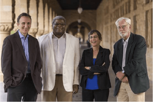 Four professionals posing confidently in a historic building corridor.