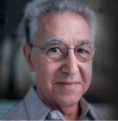 Portrait of an elderly man with glasses, smiling gently.
