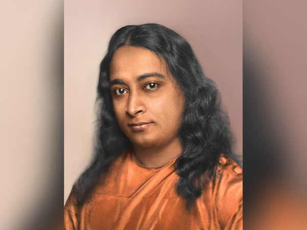 Portrait of a serene man with long hair in an orange robe.