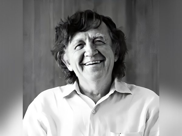 Black and white portrait of a smiling elderly man with curly hair.