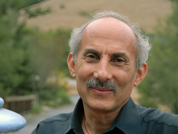 Smiling older man with gray hair outdoors.