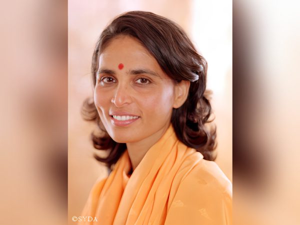 Portrait of a smiling woman with a traditional bindi and orange attire.