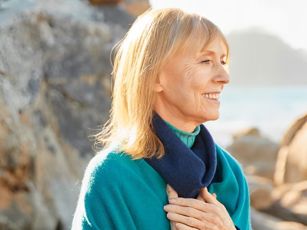 A serene woman in a teal sweater enjoys a peaceful moment outdoors.