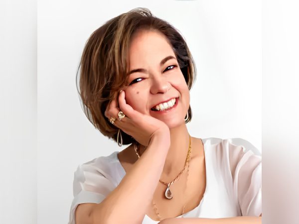 A smiling woman resting her face on her hand, radiating warmth.