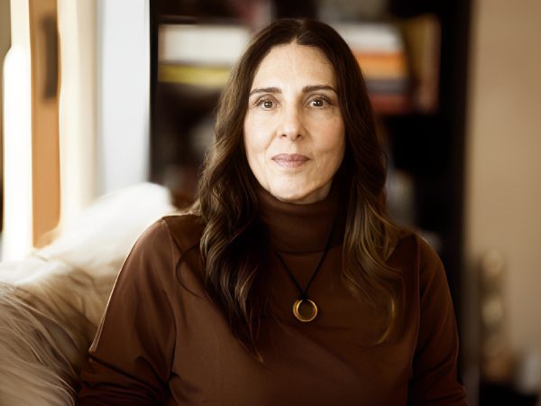 Portrait of a woman with long dark hair wearing a brown top and pendant.