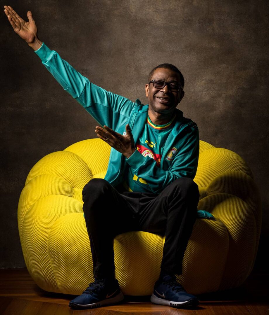 Man smiling and pointing while sitting on a yellow bean bag chair.