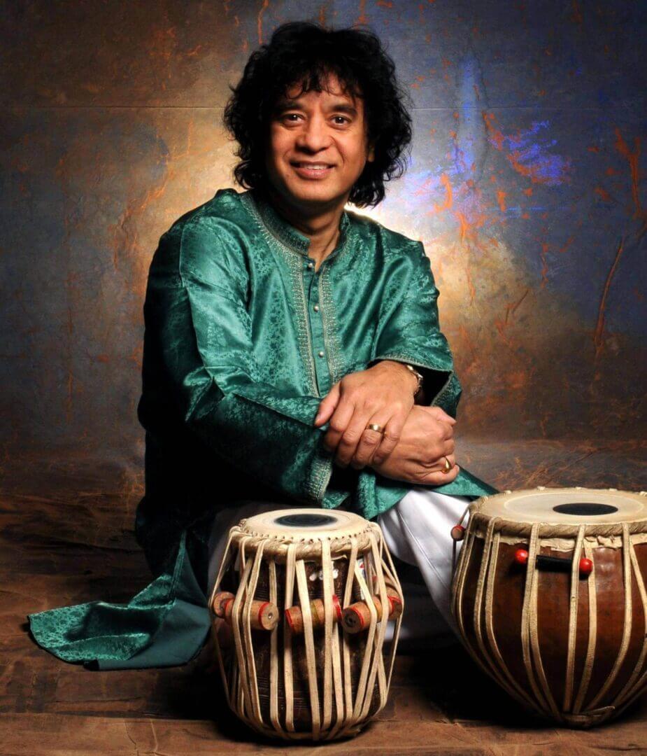 Musician playing traditional Indian tabla drums, wearing a green kurta.